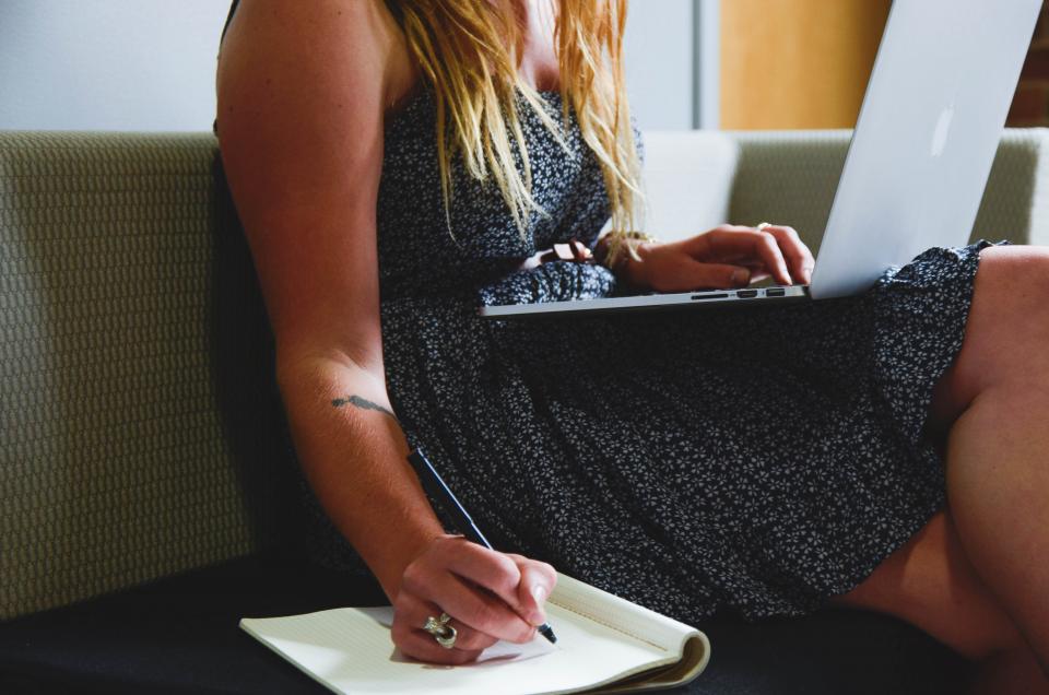 A student writing notes in a notebook while studying at home